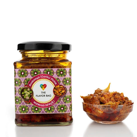 The Flavor Bag Mango Avakai Garlic Pickle in a glass jar with a small bowl of pickle. Traditional South Indian recipe.