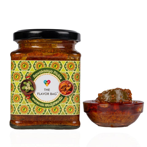 The Flavor Bag Mango Avakai Pickle in a glass jar with a small bowl of spicy green mango pickle beside it.