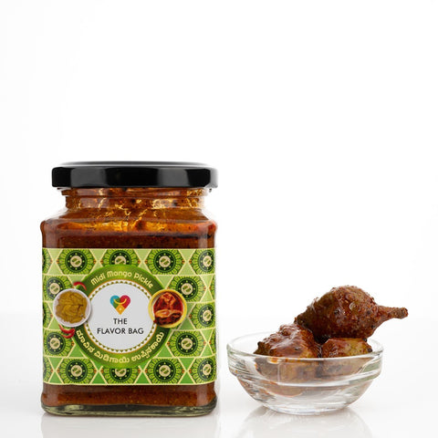The Flavor Bag Midi Mango Pickle in a glass jar with a small bowl of pickle pieces.