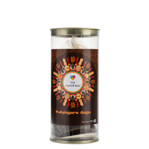 The Flavor Bag Puliyogare Gojju chutney powder in a clear cylindrical container with decorative label featuring spices and lentils.