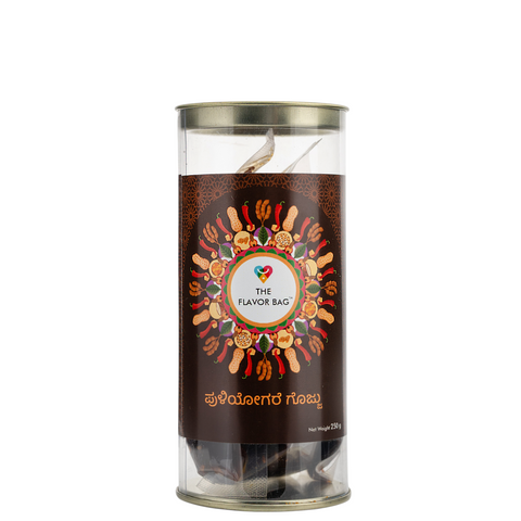 The Flavor Bag Puliyogare Gojju chutney powder in a clear cylindrical container with a decorative label.