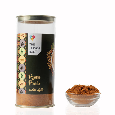 The Flavor Bag Karnataka-style Rasam Powder in a clear cylindrical container with a small bowl of spice blend.