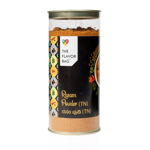 The Flavor Bag Rasam Powder TN Style in a clear cylindrical container with a black label featuring spice icons.
