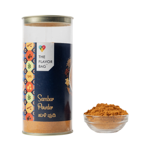 The Flavor Bag Karnataka-style Sambar Powder in a clear cylindrical container with a small bowl of spice blend